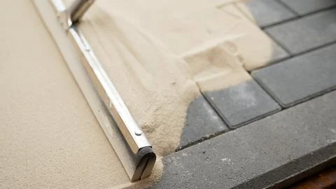 A worker with a grouting brush and spot tiles, pavement laying industry. A .. Stock Photos