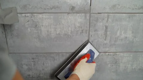 Worker grouting ceramic tiles on a wall Stock Photos