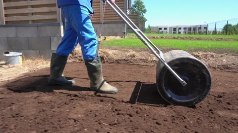 Worker in gumboots working with soil earth roller. Gimbal parallel follow shot Video stock 133021795