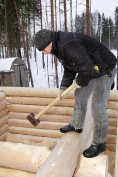 Worker with hammer aligns log wall Stock Photos