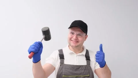 A worker with a hammer in his hands on a white background Stock Footage 256799157