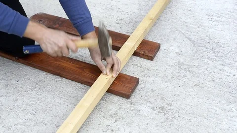 Worker hammering metal nails in a Board Stock Footage 121961489