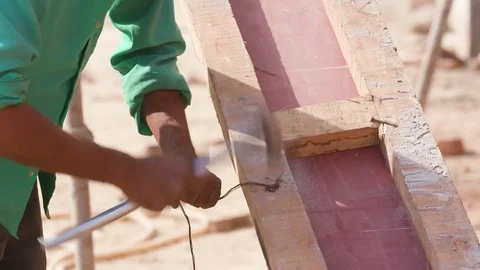 Worker hammering the nail with a strip to provide grip to the wooden plank Stock Footage 77447540