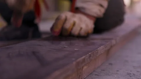 Worker hammering nail into wooden formwork board Stock Footage 346549757