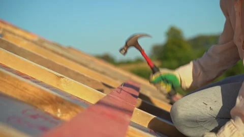 A worker hammers nails into boards close-up. Roof construction. Roof sheathing Stock-Footage 265073877