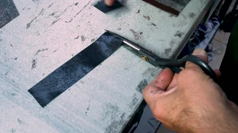 Worker Hand Cutting Leather Piece with Scissors on Factory Workbench Stock Footage 322057738