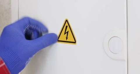 Worker hand in gloves puts sticker Danger High Voltage Stockbeeldmateriaal 302028269