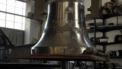 Worker Hand Moving Big Shiny Bronze Bell Suspended In Traditional Foundry - 4K Video stock 339692602