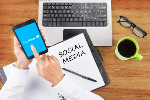 Worker hand touching twitter logo on cellphone Foto stock