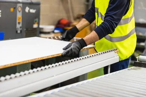 Worker handling wood panel on rollers in factory Foto stock