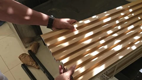 Worker hands aligning and connecting interlocking fluted wooden panels for wall Stock Footage 340001758