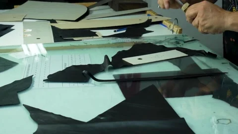 Worker Hands Arranging Pattern on Black Leather for Precision Cutting Stock Footage 322057593