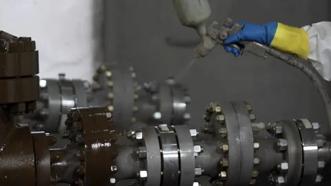 Worker hands in blue protective gloves paints oil and gas wellhead tree Stock Footage 130726428