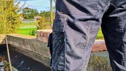 Worker hands in gloves laying red bricks on a foundation, constructing a wall Stock Footage 327627407