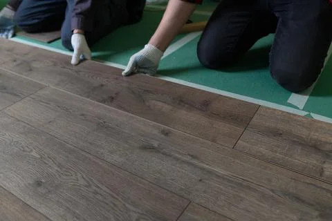 A worker hands knocking on a laminate connecting the panels with a Lock Click Stock Photos