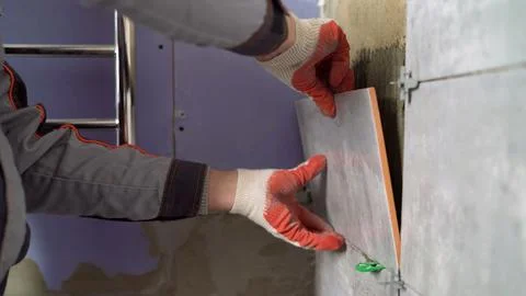 Worker hands laying ceramic wall tile during renovation Stock Photos