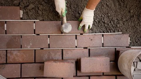 Worker hands laying interlocking pavement bricks with rubber mallet Stock Photos