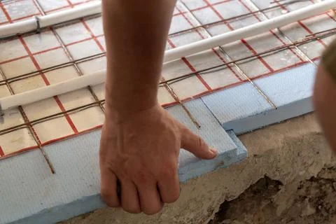 Worker hands mounting underfloor heating pipes on foam board insulation bef.. Stock Photos