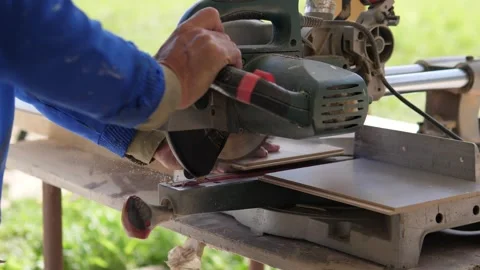 Worker hands position wood boards beside powered miter saw on outdoor workbench Stock Footage 344873391