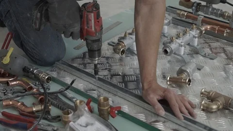 Worker hands prepare with drill heating system. Plumber mounted distributor of Stock Footage 99703681