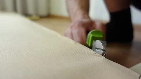 Worker hands removing old upholstery from part of the bed with staple remover Video stock 168643552