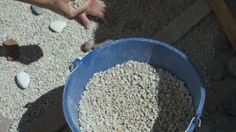 Worker hands scooping gravel into blue bucket Stock Footage 336408717