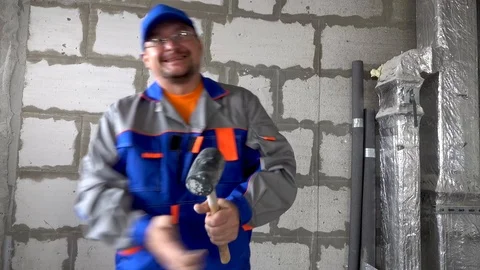 Worker in the hands of a sledgehammer is very angry and beats Stock Footage 115419112