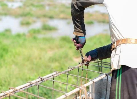 Worker hands tying metal structure using pliers, creating strong iron frame.. Stock Photos