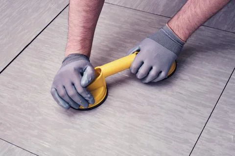 Worker hands with vacuum suction cups for lifting floor panels. A man lifts a Stock Photos