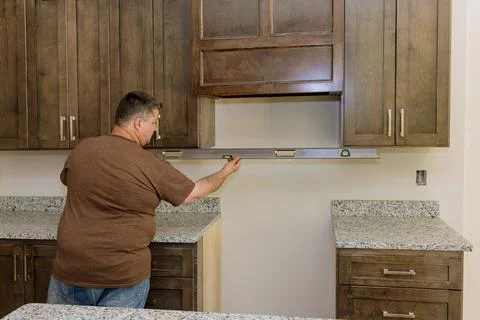 Worker hanging a level in preparation for the leveling of a new kitchen cabinet Stock-Fotos