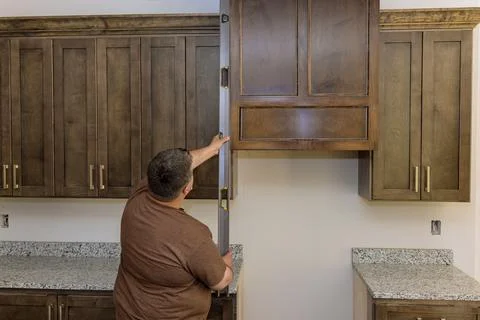 A worker hangs a level at the site for the leveling of new kitchen cabinets and Stock Photos