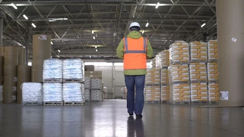Worker in hard hat and orange uniform walking and talking by cellphone in Video stock 101233980