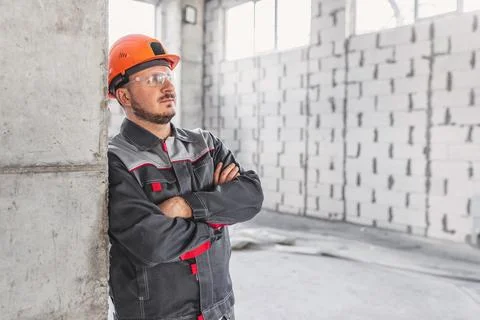 Worker in hard hat and protective glasses at a construction site near a Stock Photos