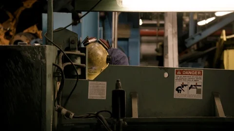 Worker in hard hat at lathe working with head down in Modern Factory Stock Footage 89944639
