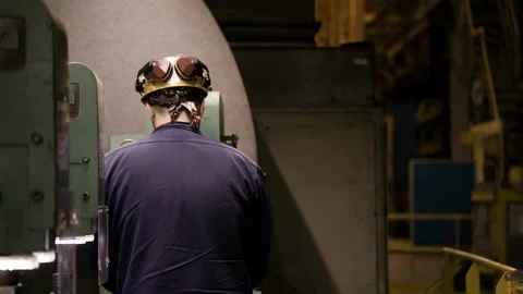 Worker in hard hat at milling machine turns towards camera and exits Stock Footage 89944622