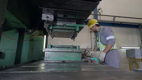 Worker in hard hat operates heavy industrial press machine 库存影片 346153169