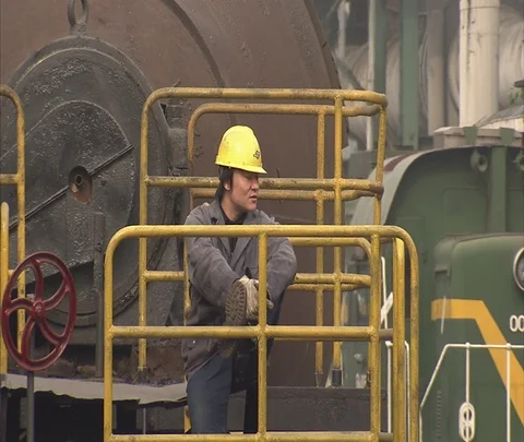 Worker in hard hat rides on back of train crossing at coal burning power plant Stock Footage 86806141