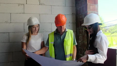 Worker in hard hat shows layout to female engineers Stock Footage 317608960