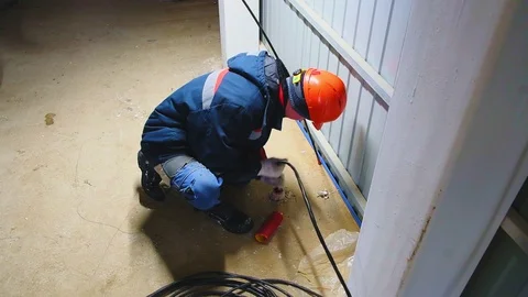 Worker in hardhat puts cable into hole on floor at station 스톡 동영상 127755438
