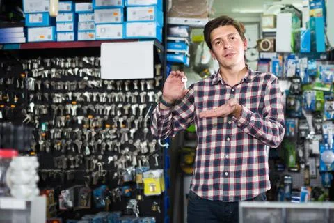 Worker in hardware store trading goods and keys in uniform Foto stock