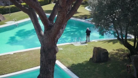 Worker in a hat cleans the pool. Light ripples and sun glare on turquoise water Stock Footage 154822638