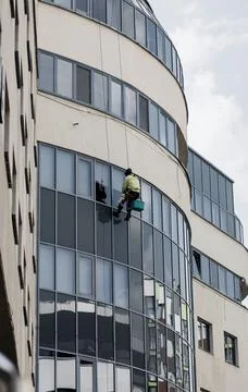 A worker at a height washes the windows Stock Photos
