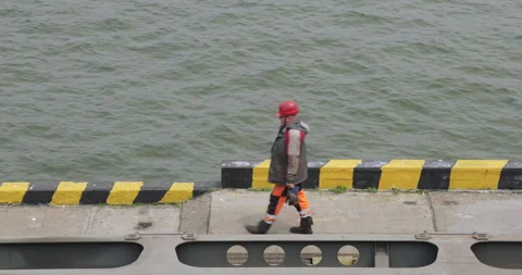 Worker in helmet and reflective vest walks along pier Видео 319832234