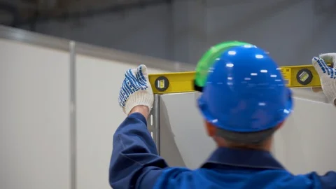 Worker in helmet checks level evenness and horizontality of installed metal box Stock Footage 126356328