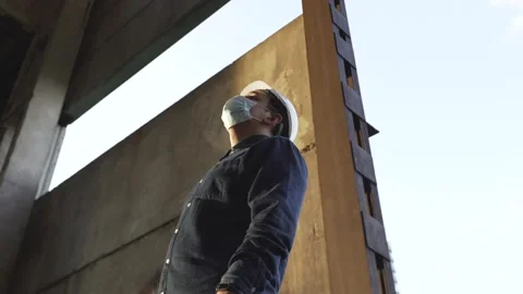A worker in a helmet at a construction site puts on a protective mask Stock Footage 138147467