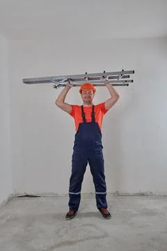 A worker in a helmet stands with a stepladder Stock Photos