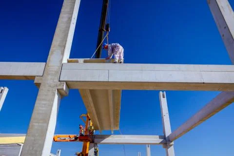 Worker is helping crane to keep balance and direction of concrete joist Stock Photos