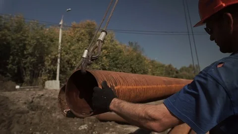 Worker helps the crane operator to stack piles, pipes 库存影片 71219545
