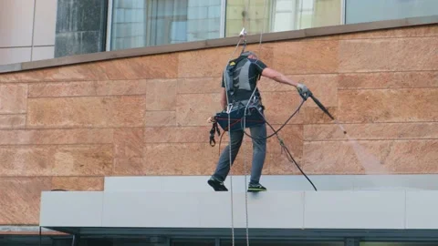 Worker high-rise washes the facade of the building with a high-pressure wash Vídeo Stock 156793057