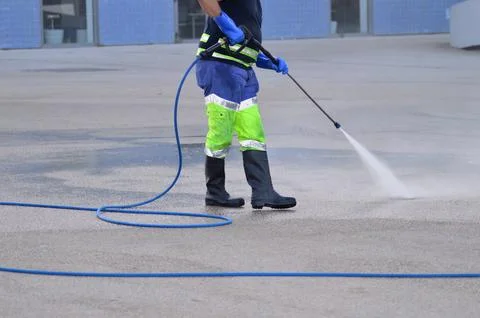 Worker in high visibility work clothes washing streets with water jet Stock Photos